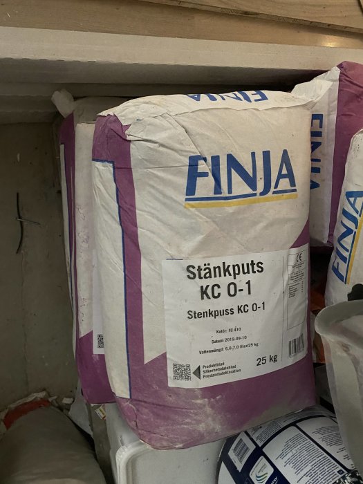 Säckar med Finja stänkputs staplade i ett förråd, redo att hämtas.