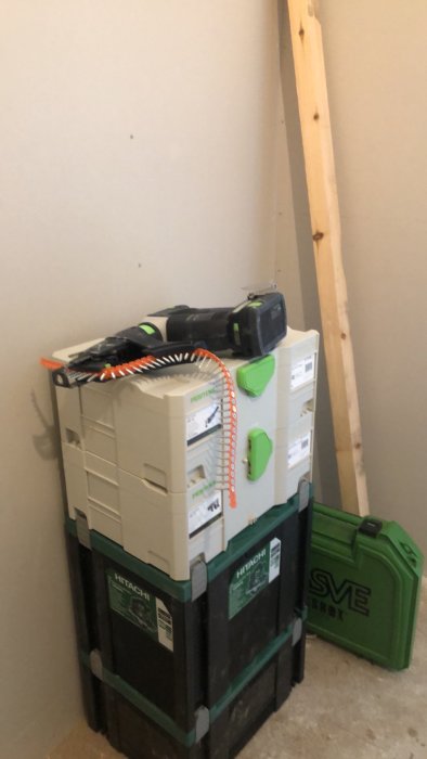 Renoveringsprojekt med osynliga gipsskivor och verktygsboxar från Festool och Hitachi i ett ofärdigt rum.