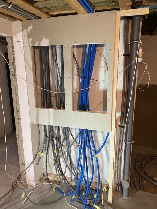 En öppen vägg med nyinstallerad elnisch och synliga elledningar såväl som VVS-installationer under arbete.