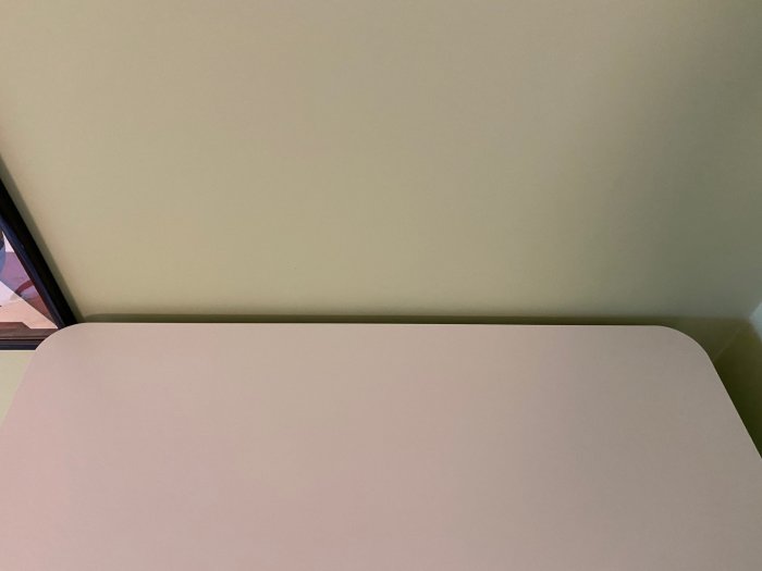 Översikt av toppen på ett lågt Ikea klädskåp mot en vägg med synlig glipa orsakad av tjock golvsockel.