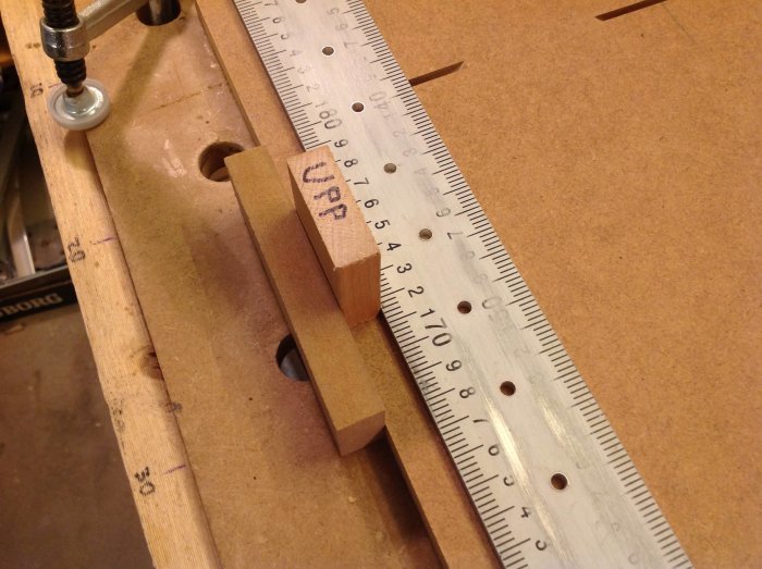 Träarbetsbänk med hålmall, aluprofil och trädistans, använd för att borra precisionshål i ett projekt.