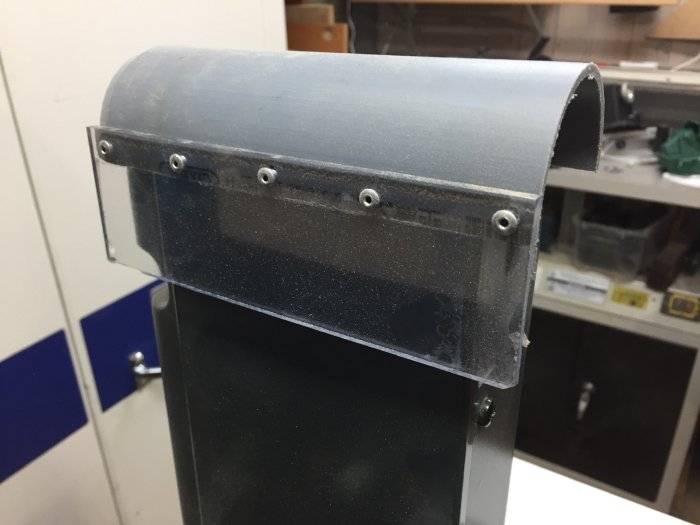 Plaströr nitat i plexiglas ovanpå slipmaskin för dammuppsamling, täckt med gummiduk.