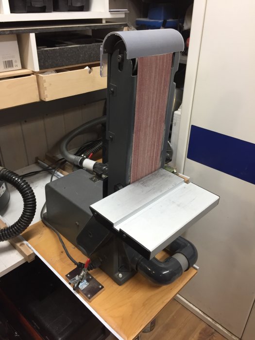 Stående bänkslip med anhåll vid 90 grader och anordningar för uppsamling av slipdamm.