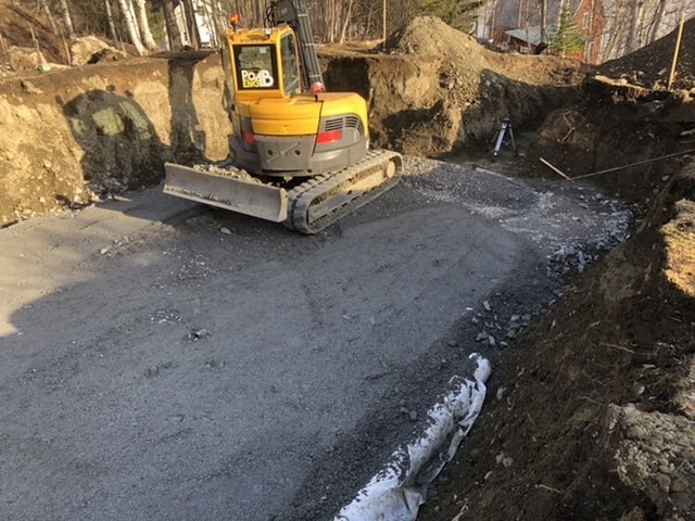 Grävmaskin på ett bygge med nylagt grus som underlag på marken.