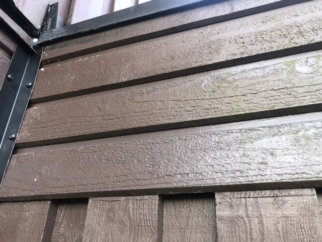 Liggande bruna träpaneler på husvägg med synliga förhöjningar uppskattningsvis 65mm, mossa syns på övre panel.