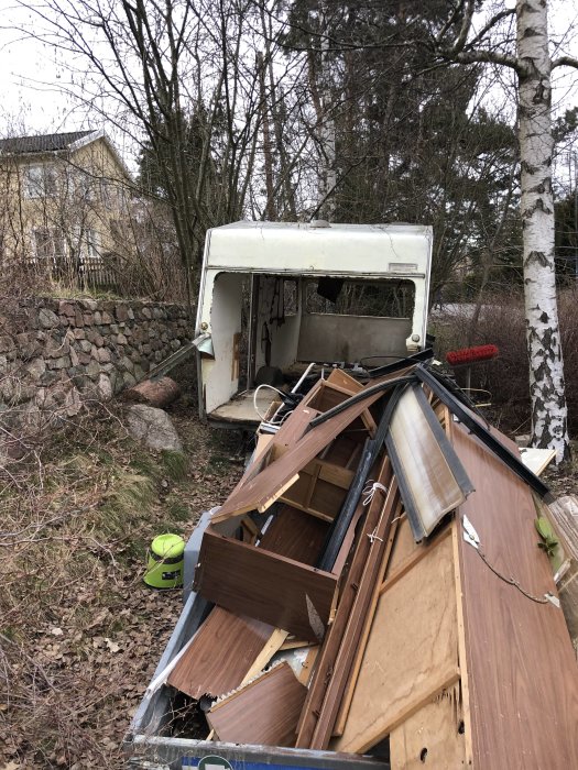Ett demonterat chassi från en vagn och en hög med rivna trämöbler utomhus.