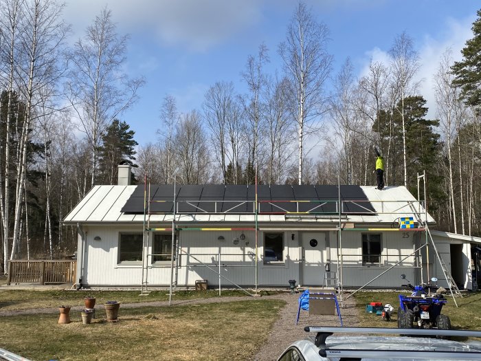 Installation av solcellspaneler på en villa med ställningar och arbetare på taket.