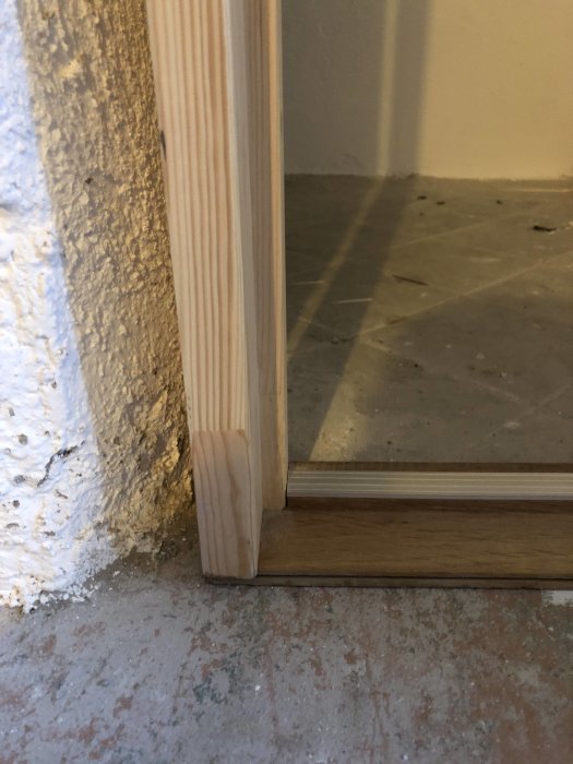 Närbild på fasat dörrhål med luftspalt mellan dörrkarm och betongvägg vid källarrenovering.