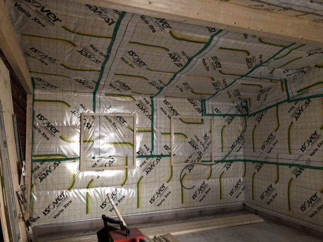 Utbyggnad med isoleringsmaterial på väggar och tak, träreglar synliga, redo för installationskikt.