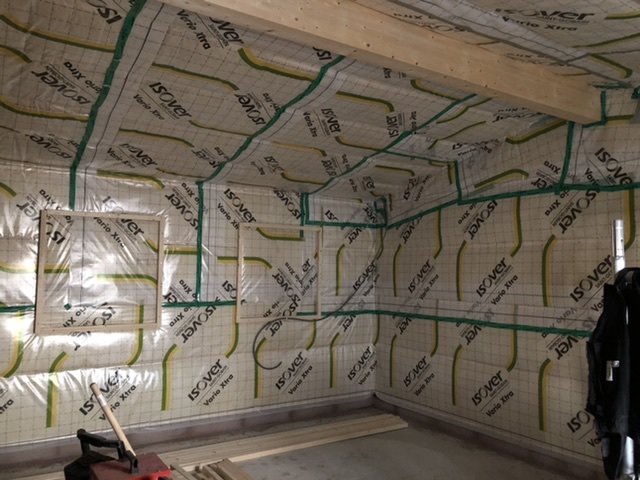 Isolerat utrymme under konstruktion med synliga installationer och isoleringsmaterial på väggar och tak.