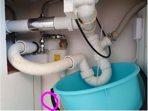 VVS-installation med synligt utlopp och slangar i skåp, rosa markering där anslutning bör vara.
