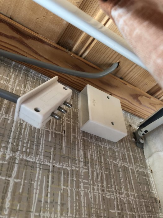 Elektrisk kontakt och dosa monterade nära tak, bakom gardin i en stuga.