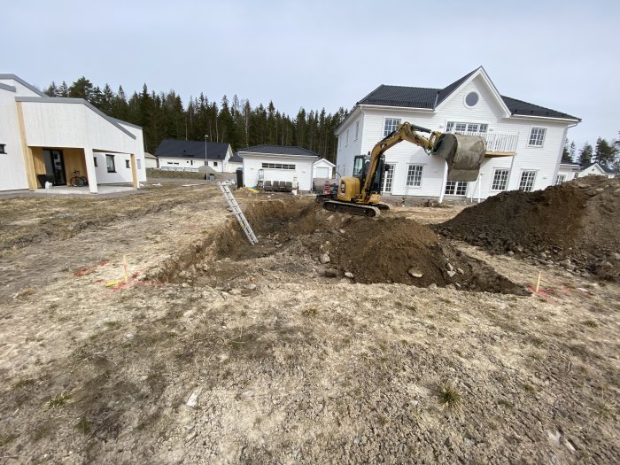 Grävmaskin schaktar mark för poolinstallation i bostadsområde med vit villa i bakgrunden.