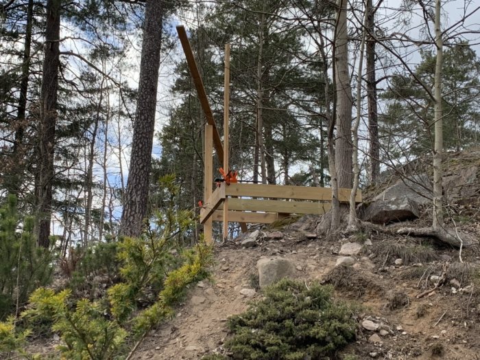 Påbörjad träkonstruktion av en lekstuga i skogsmiljö med verktyg synliga på golvet.