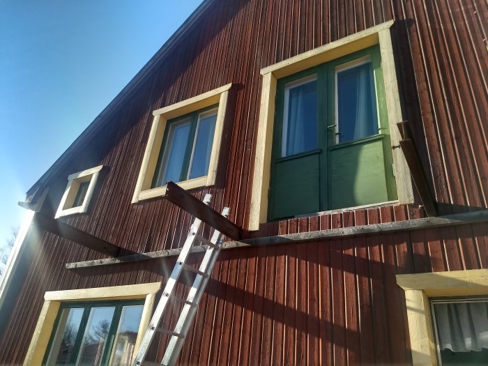 Villa med träfasad och tre utstickande järnbalkar från en rivningsplats för balkong.