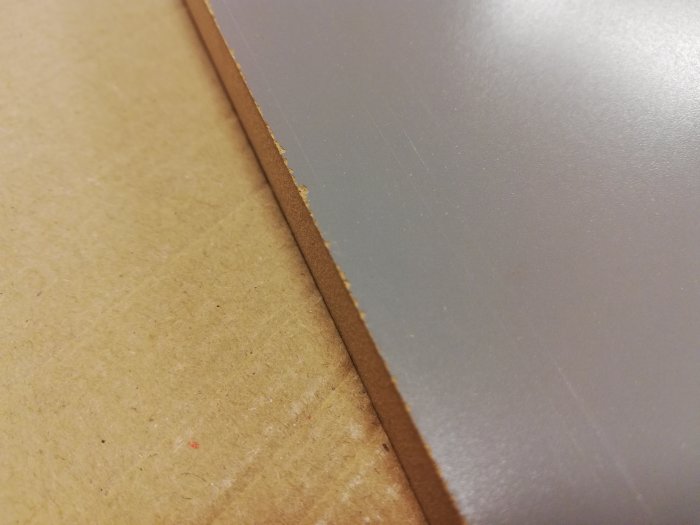 Skivad kant på MDF-panel där snittytan uppvisar fransiga fibrer.