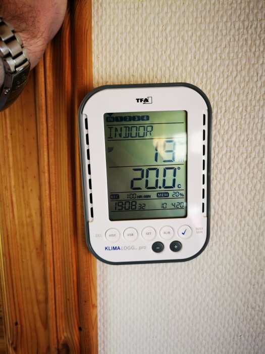 Hygrometer visar 19% relativ luftfuktighet på vägg med träpanel.