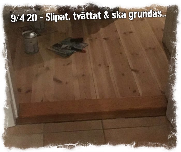 Trägolv som är slipat och redo för grundning, med slipmaskin och tidningar på golvet.