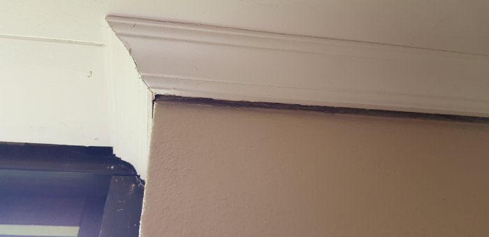 Spricka där tak och vägg möts i ett hörn, tecken på eventuella sättningsskador i huset.