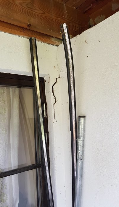 Sprickor i vägg intill fönstret och golvlister i en gillestuga, tecken på att huset sätter sig.
