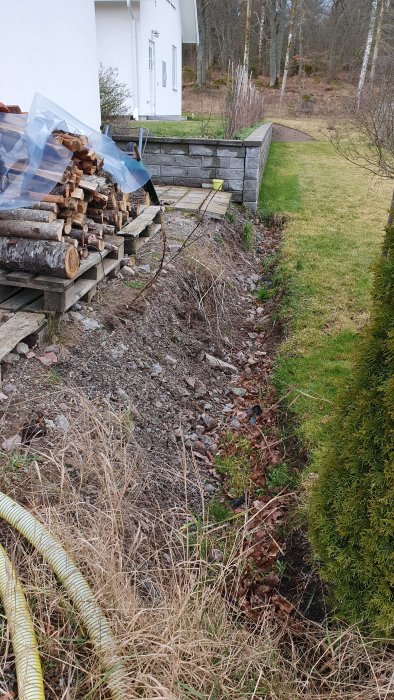 Dike längs gräsmatta och grusyta med ojämn nivå och 30 cm djup, förberedelse för staketbygge.