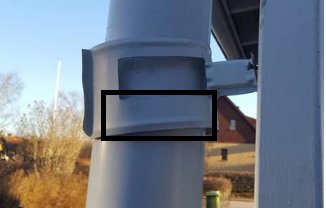 Del av stolpe med bredare övre del monterad mot en annan stolpsektion, utomhus.