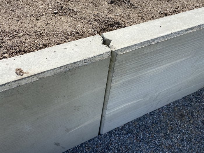 Nya L-stöd i betong med hålrum mellan skärmarna och nylagd jord ovanpå.