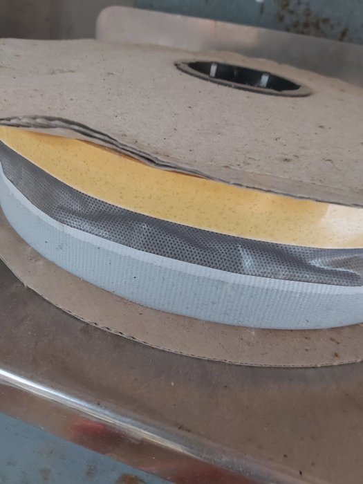 Rulle med gul skumremsa och grå klisterremsa på båda sidor, staplade på en horisontell yta.