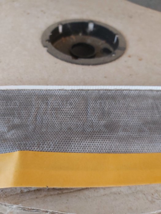 Rulle med oidentifierat byggmaterial med klisterremsor och nätstruktur.