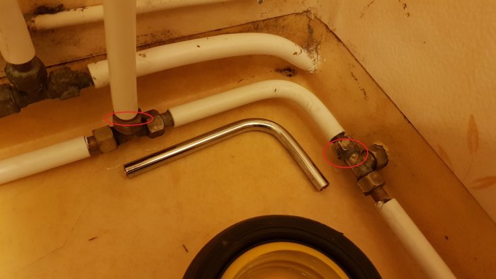 En bild av VVS-rörinstallationer där läckage är markerat på en mässingsgänga till höger och vid en mutter till vänster.