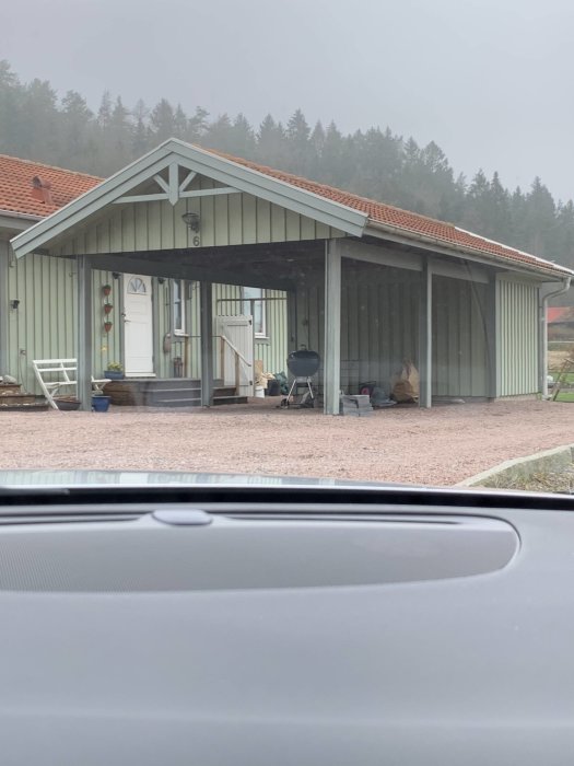 Carport med grön takbeklädnad ansluten till ett hus, utan förråd på baksidan.