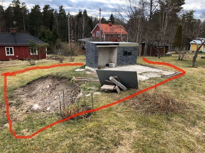 Markeringar på marken för planerat trädäck runt en grillplats i en trädgård med höjdskillnad.