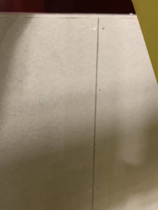 Bygggipsskivor staplade, skugga till höger, synlig skarv och skruv, mot mörk bakgrund.