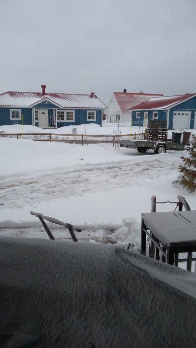 Uppfarter och hus täckta av ett tjockt lager snö i slutet av vintersäsongen.