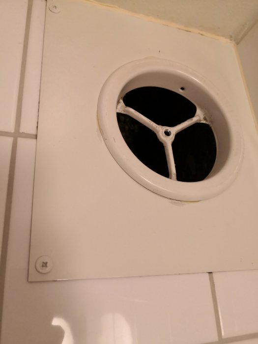 Ventilationsutsug utan skydd på badrumsvägg, synligt schakt och murbruk, 11,5 cm diameter.