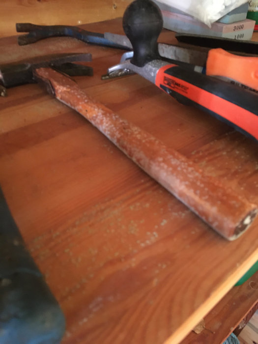 Verktyg med mögelpåväxt på ett trähylleplan, indikerande fuktproblem i boden.