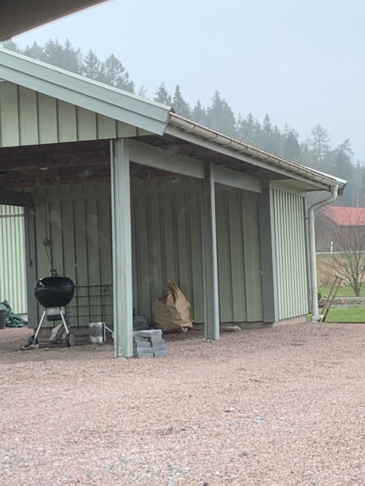 Carport med synliga trästolpar och takkonstruktion i grått väder.