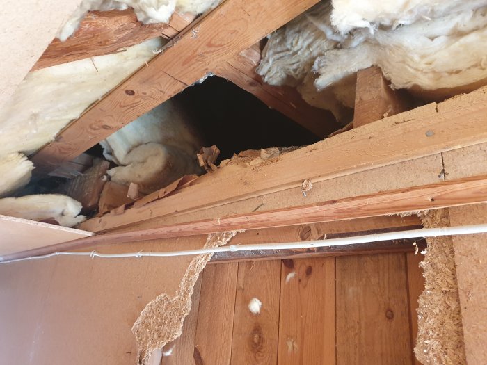 Rivet kattvind med exponerade träreglar och gammal isolering i ett hus från 1930-talet, där renoveringsarbete pågår.