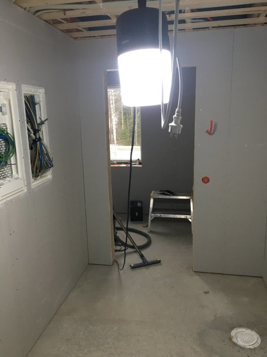Pågående arbete i en oinredd tvättstuga med oskyddad kablage och byggmaterial.