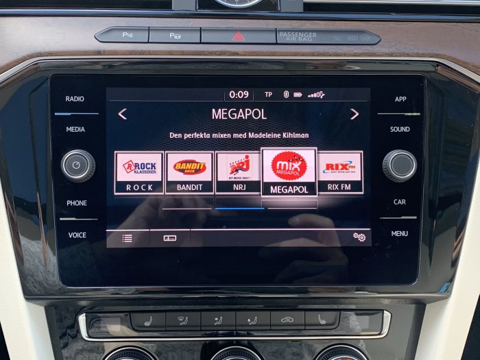 Uppdaterad bilstereo med stor skärm som visar radiostationer och menyalternativ.