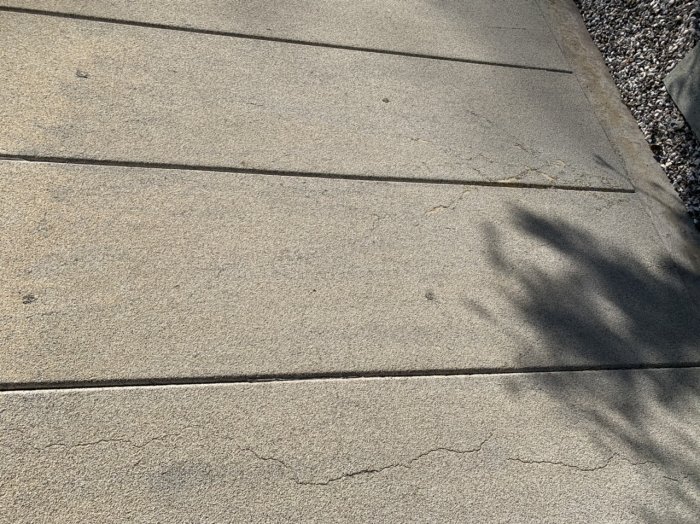 Bild på ett stenliknande ytskikt med sprickor och slitage på garagevägg.