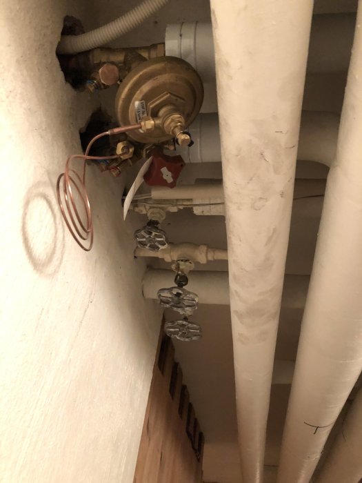 VVS-installation med flera avstängningsventiler och rör vid ett väggutrymme.