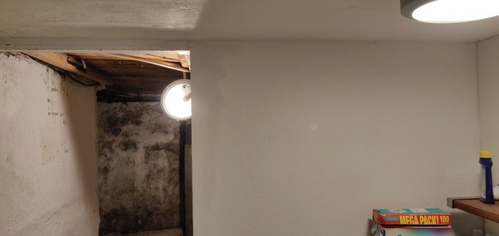 Källarvägg där en del av en bärande vägg är borttagen, exponerade takbjälkar och takhöjd.