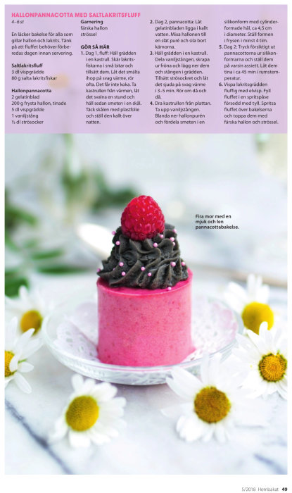 Rosa hallonpannacotta med lakritsfluff toppad med ett hallon och små sockerpärlor, omgiven av prästkragar.
