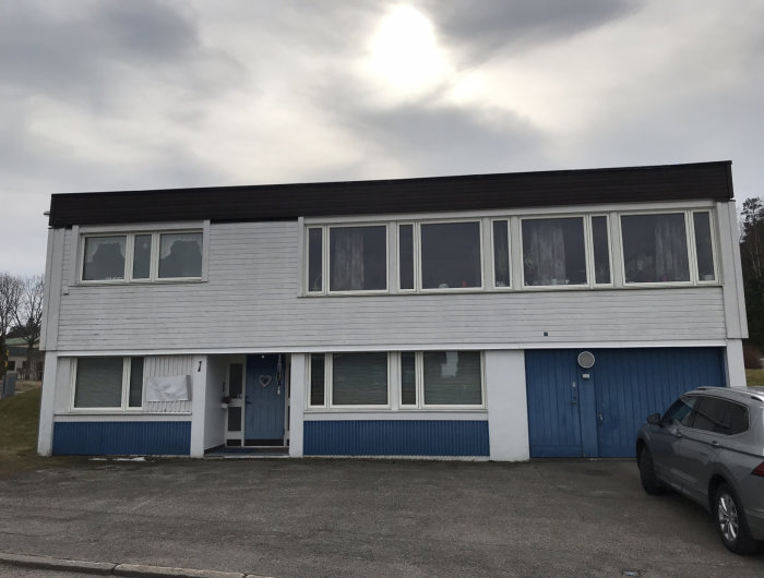 Sutteränghus med vit och blå fasad, två våningar med framtida renoveringspotential.