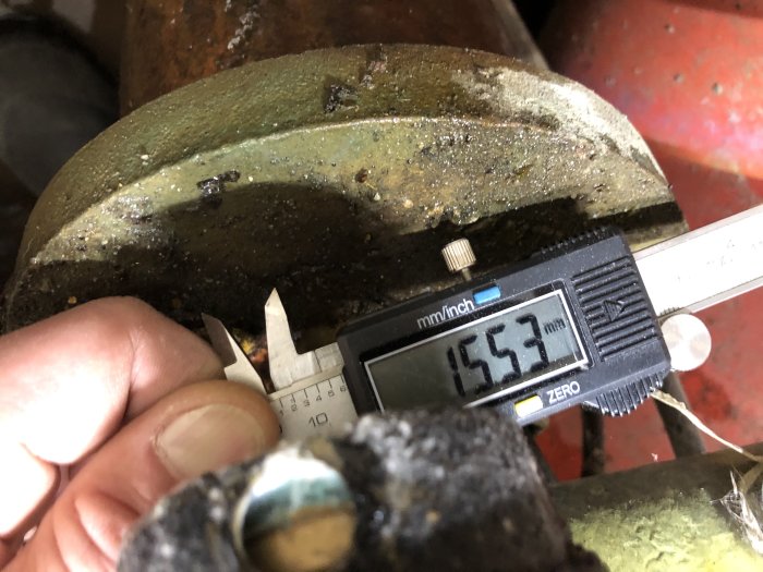Digital skjutmått mäter en mutters diameter på en rostig rörkoppling.