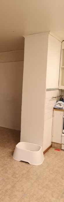 <!-- En renoveret murstock i et rum med hvidmalet væg, fliser og en hvid foderskål på gulvet. -->