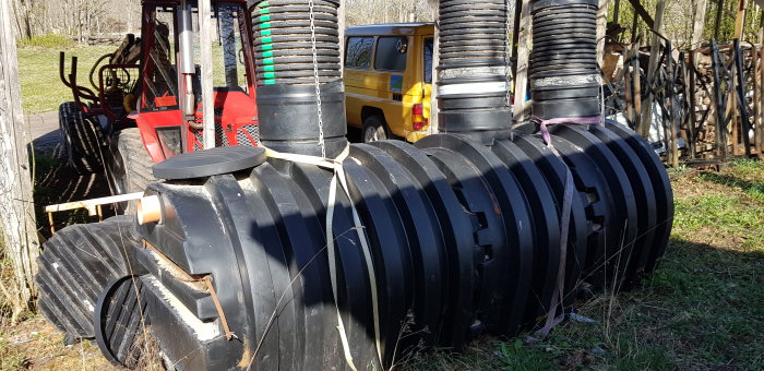 Plastbrunn med texten "Upunal" i ett utomhusmiljö vid sidan av en gaffeltruck och en gul skåpbil.