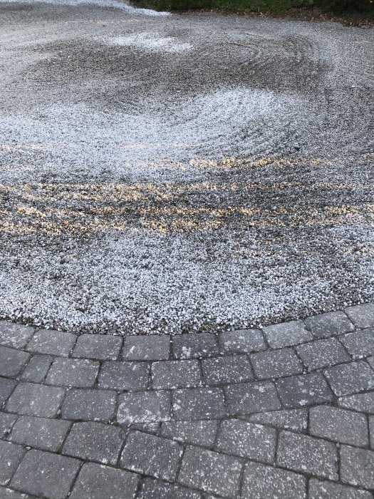 Grusgång med nyutlagd vit kvartsit intill äldre grå sten, skillnad i färg mellan ljus och mörk grus.