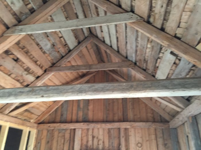 Inredningen av ett uthus med synligt träbjälklag och takstolar, ett renoveringsprojekt under planering.